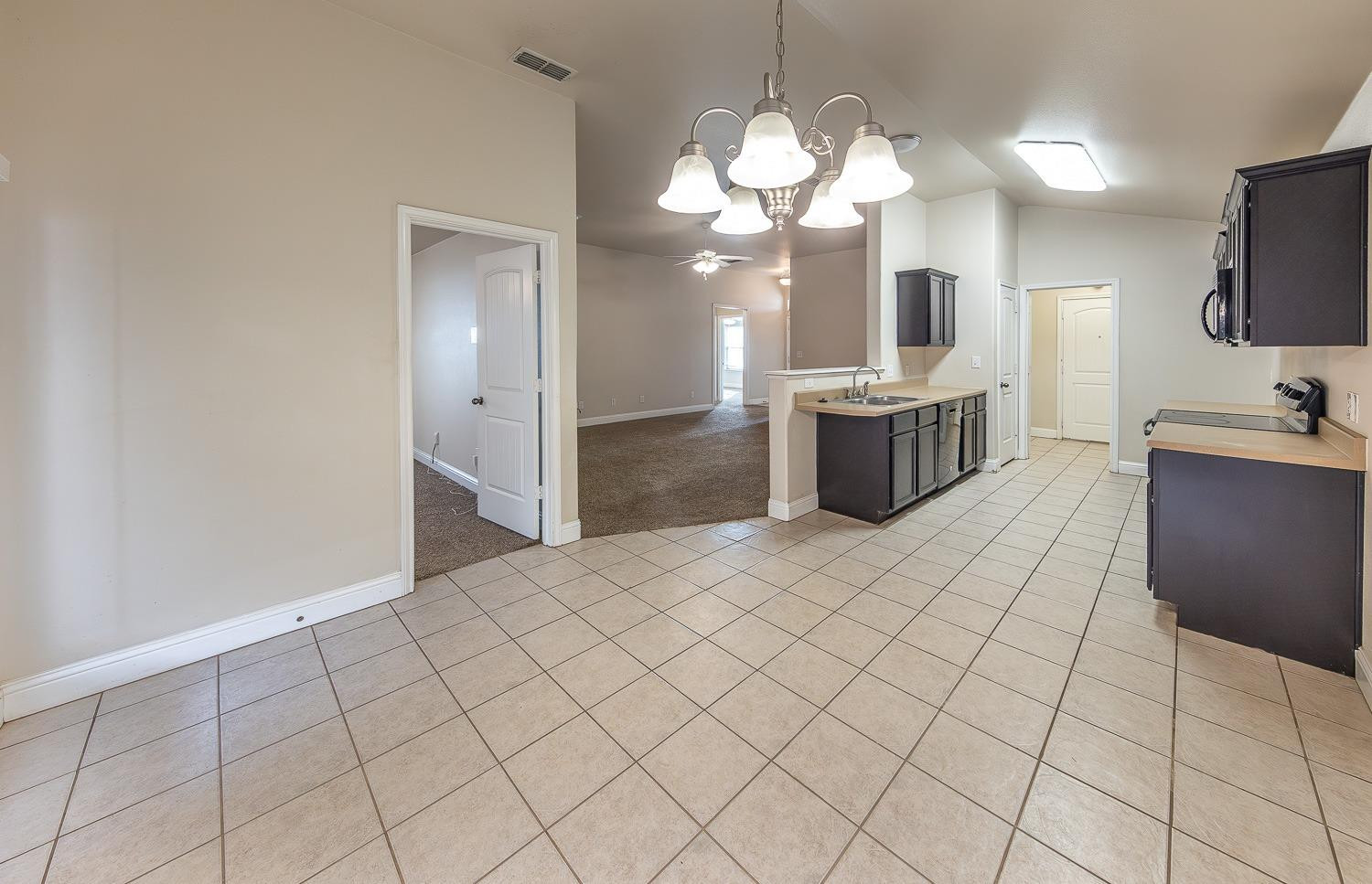 5504 110th Street Lubbock, TX 79424 - Photo 9 of 23 a large white kitchen with a sink and chandelier