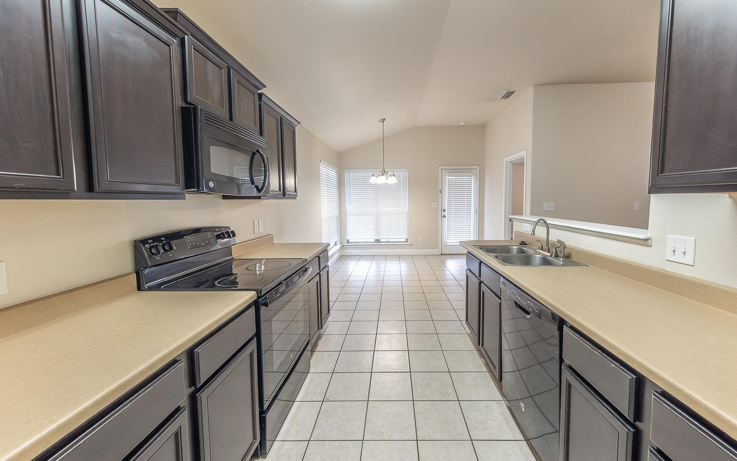 5504 110th Street Lubbock, TX 79424 - Photo 10 of 23 a kitchen with stainless steel appliances a sink a stove top oven a counter space and cabinets