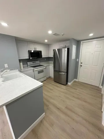 a kitchen with stainless steel appliances kitchen island granite countertop a refrigerator a sink a stove and oven