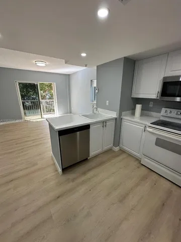 a large kitchen with stainless steel appliances granite countertop a stove a sink and a microwave