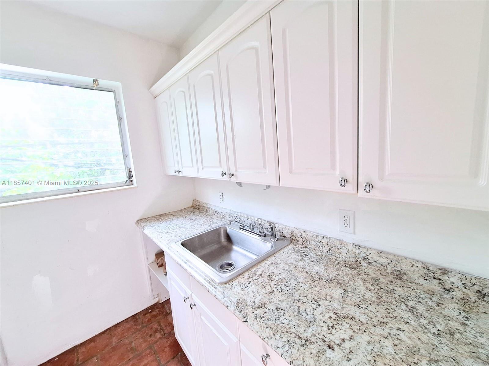 1770 Meridian Avenue, Unit 207 Miami Beach, FL 33139 - Photo 11 of 26 a kitchen with a sink window and cabinets