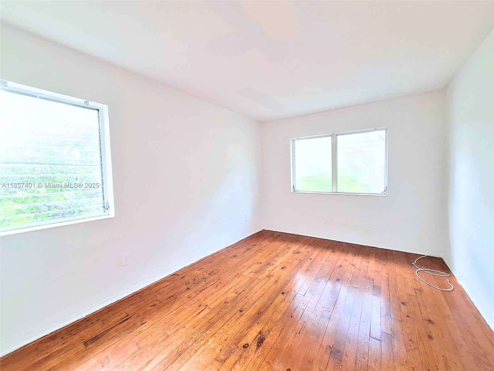 1770 Meridian Avenue, Unit 207 Miami Beach, FL 33139 - Photo 4 of 26 an empty room with wooden floor and windows