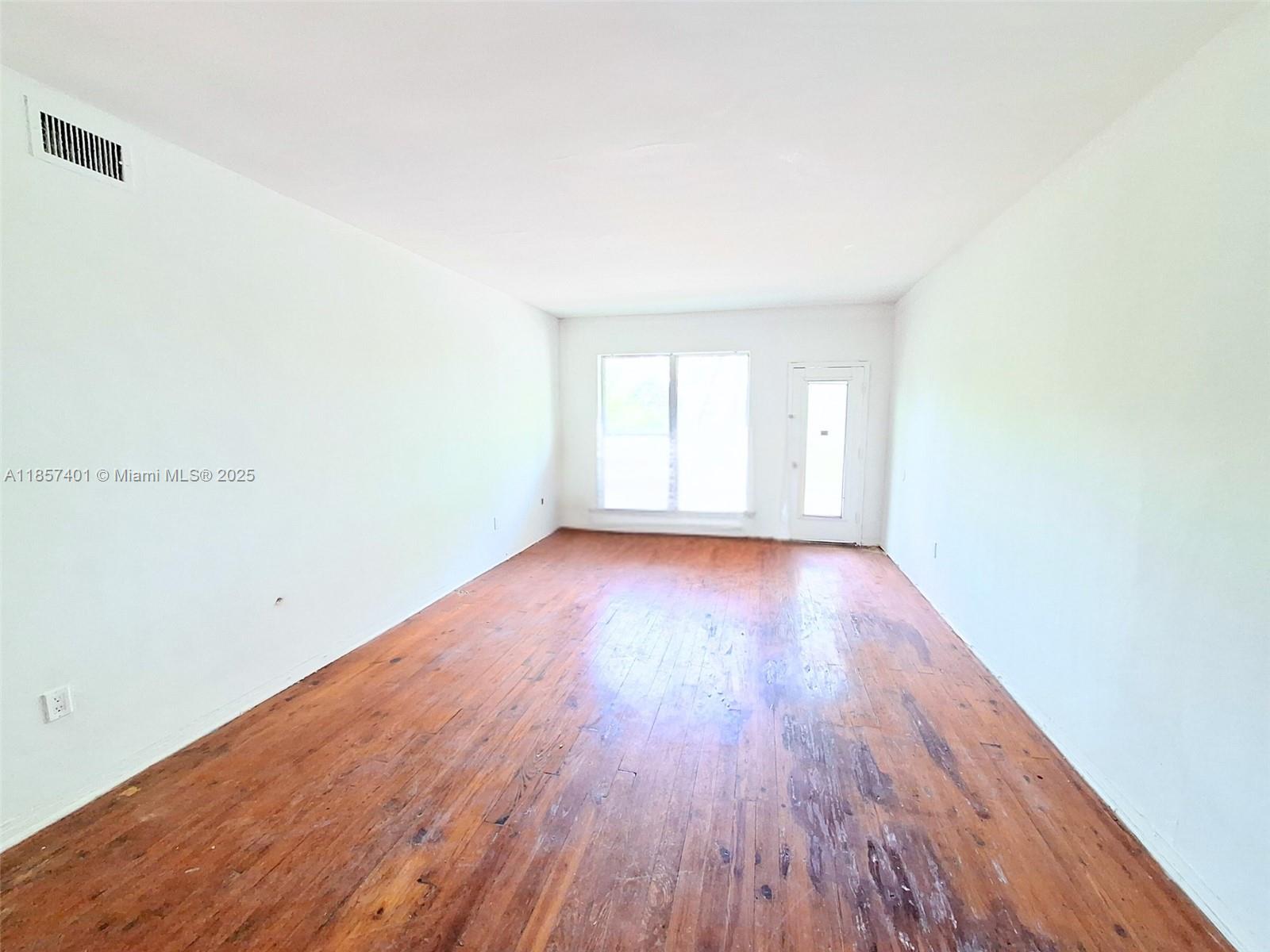 1770 Meridian Avenue, Unit 207 Miami Beach, FL 33139 - Photo 9 of 26 an empty room with wooden floor and windows