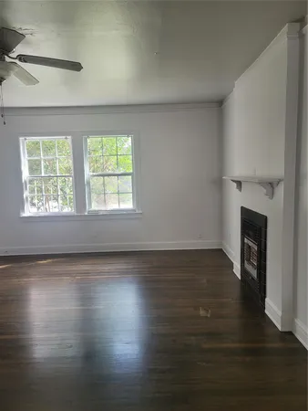 an empty room with wooden floor fireplace and windows