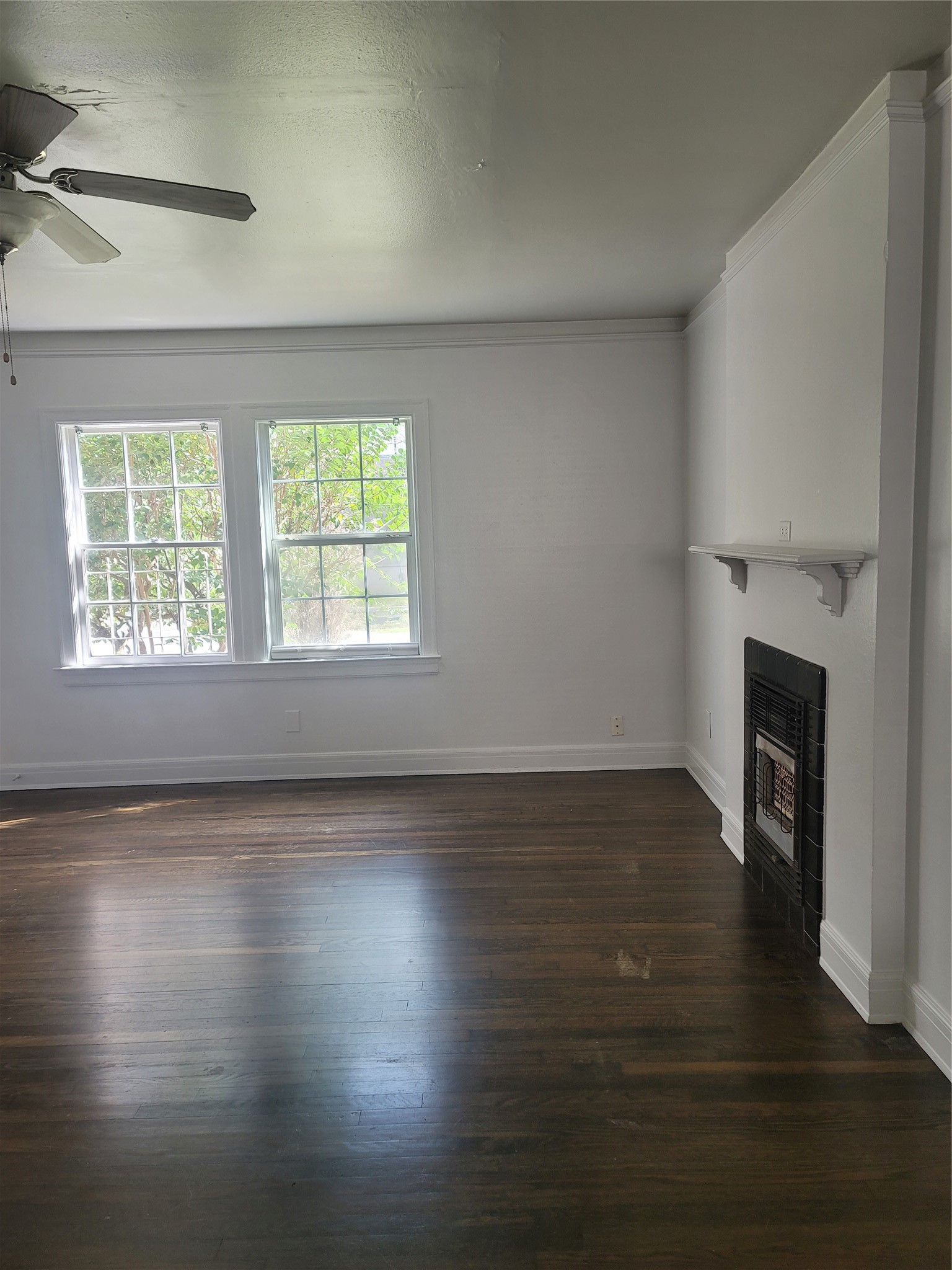 an empty room with wooden floor fireplace and windows