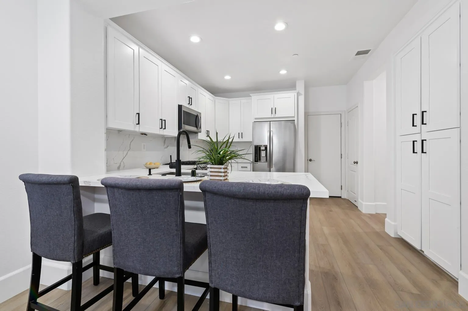 13002 Requlo Place San Diego, CA 92130 - Photo 4 of 17 a kitchen with kitchen island a dining table chairs stainless steel appliances and cabinets