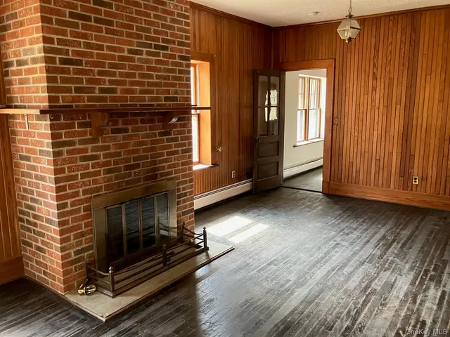 a view of an empty room with wooden floor and a fireplace