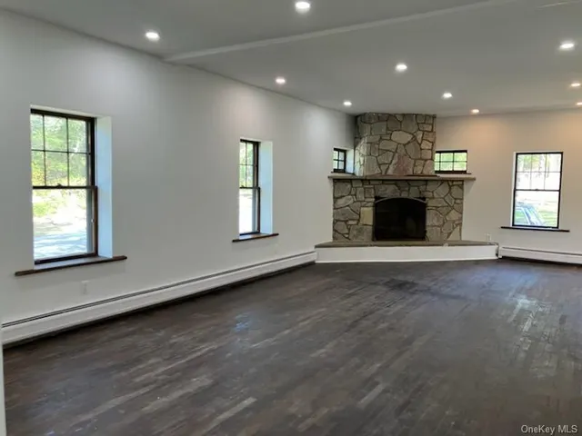 an empty room with wooden floor fireplace and windows