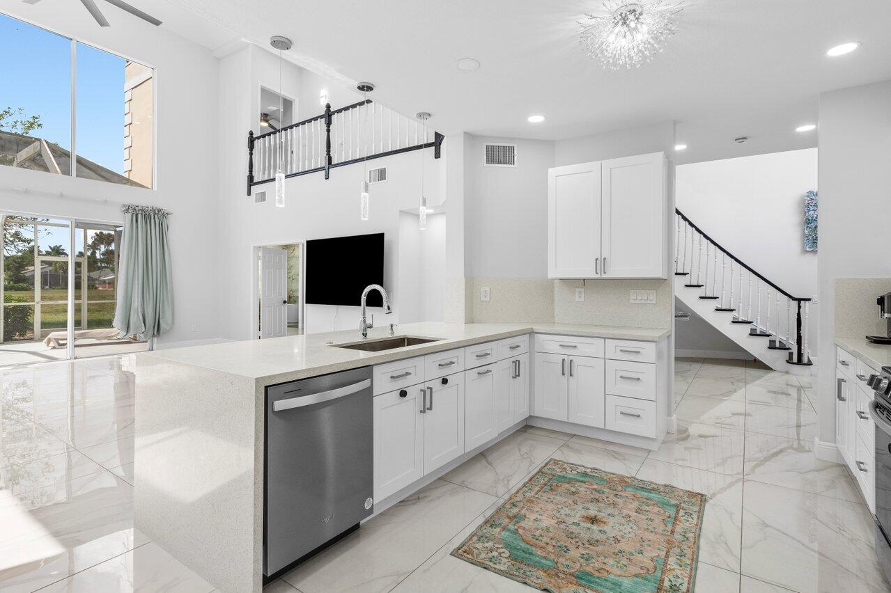 7748 Travelers Tree Drive Boca Raton, FL 33433 - Photo 13 of 35 a large white kitchen with stainless steel appliances granite countertop a sink and a stove