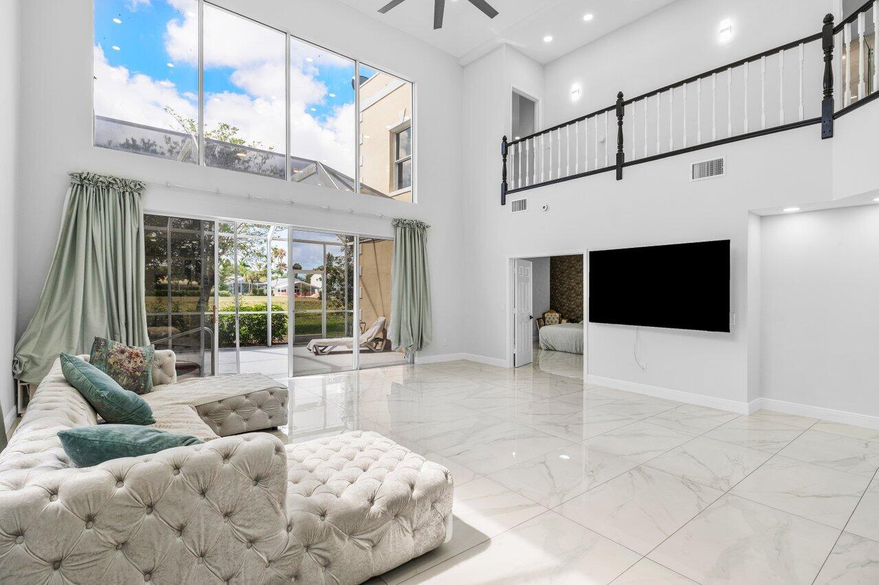 7748 Travelers Tree Drive Boca Raton, FL 33433 - Photo 8 of 35 a living room with furniture a flat screen tv and a floor to ceiling window