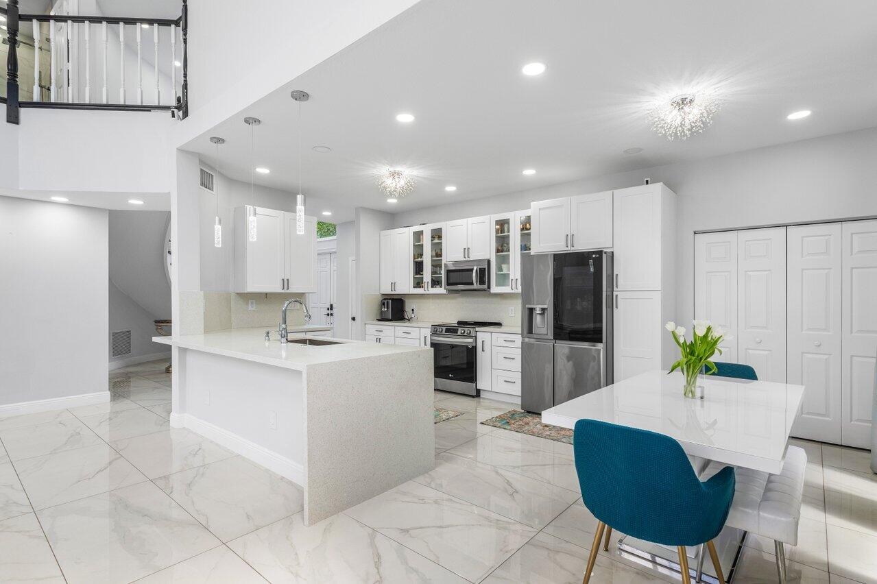 7748 Travelers Tree Drive Boca Raton, FL 33433 - Photo 9 of 35 a kitchen with refrigerator and chairs