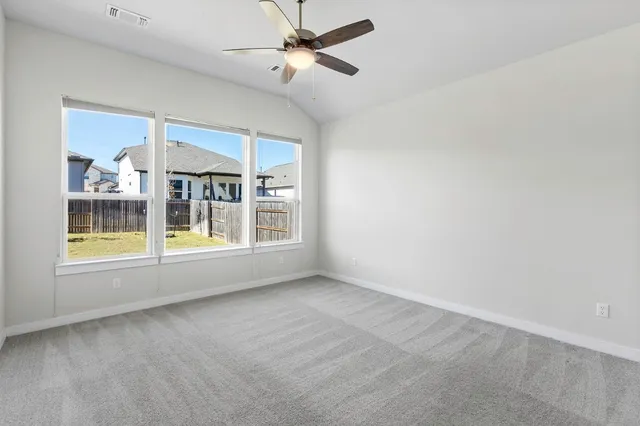 an empty room with windows and fan