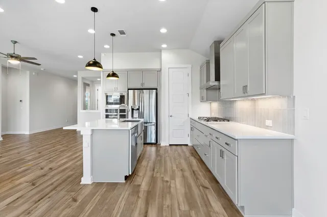 a kitchen with kitchen island a sink a counter top space stainless steel appliances and cabinets
