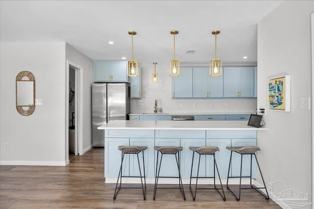a kitchen with stainless steel appliances granite countertop a table chairs and a refrigerator