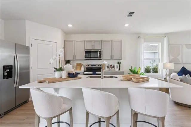 a kitchen with a refrigerator a stove a sink and chairs