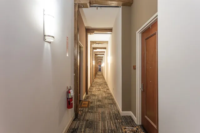a view of a hallway with wooden floor and a bathroom