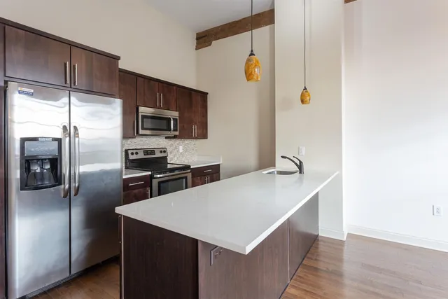 a kitchen with stainless steel appliances a sink a microwave a refrigerator and wooden floor