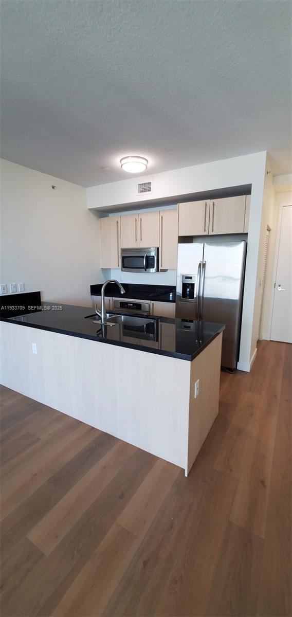 79 Southwest 12th Street, Unit 2411S Miami, FL 33130 - Photo 3 of 23 a view of a kitchen with kitchen island a sink wooden floor and black appliances