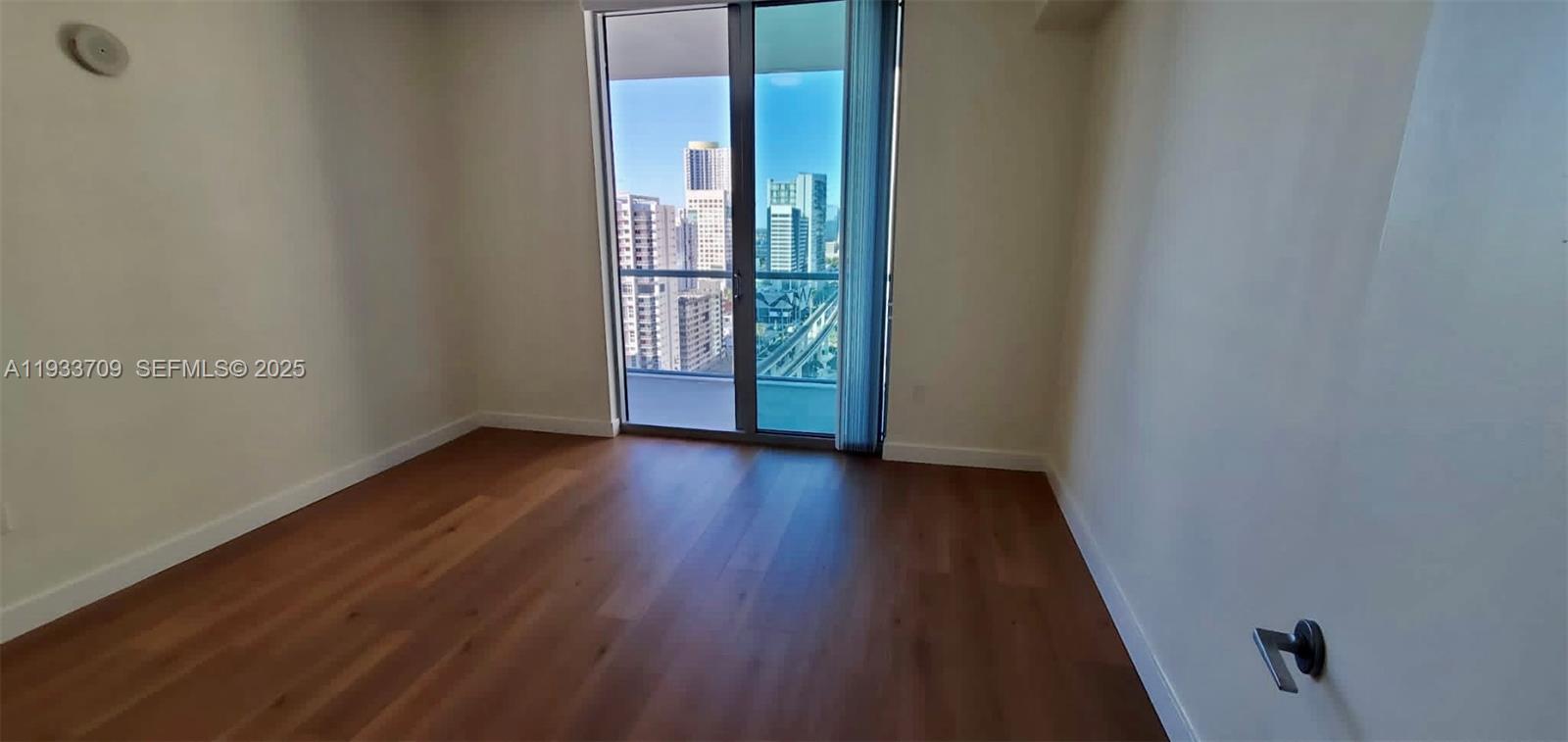 79 Southwest 12th Street, Unit 2411S Miami, FL 33130 - Photo 6 of 23 a view of an empty room with wooden floor and a window