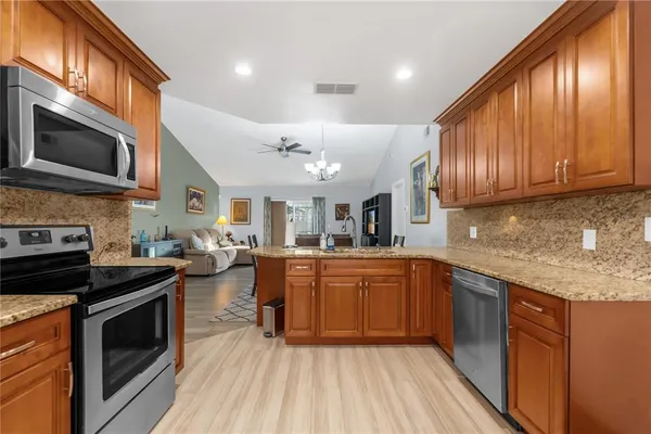 a kitchen with stainless steel appliances granite countertop wooden cabinets a stove top oven a sink and dishwasher