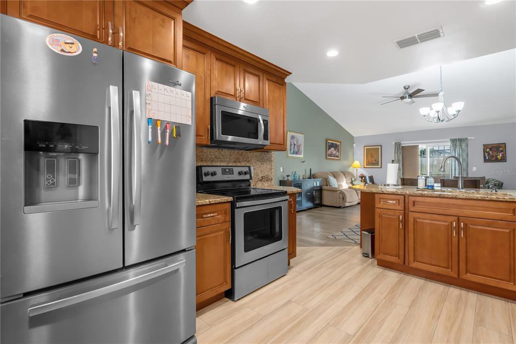 7702 Legacy Lane Orlando, FL 32818 - Photo 14 of 21 a kitchen with stainless steel appliances granite countertop a refrigerator a stove top oven a sink dishwasher and wooden cabinets with wooden floor