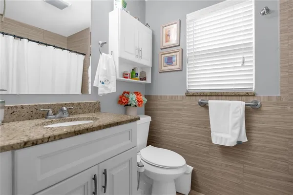 a bathroom with a granite countertop sink and a toilet