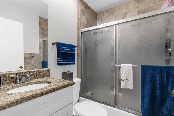 a bathroom with a granite countertop sink a toilet and shower
