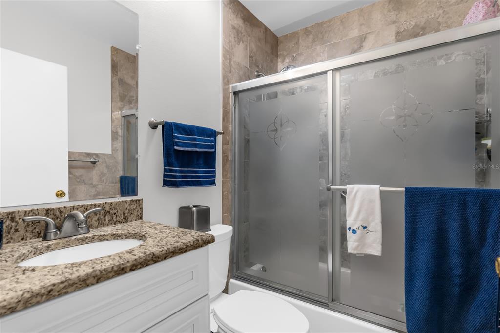 7702 Legacy Lane Orlando, FL 32818 - Photo 19 of 21 a bathroom with a granite countertop sink a toilet and shower