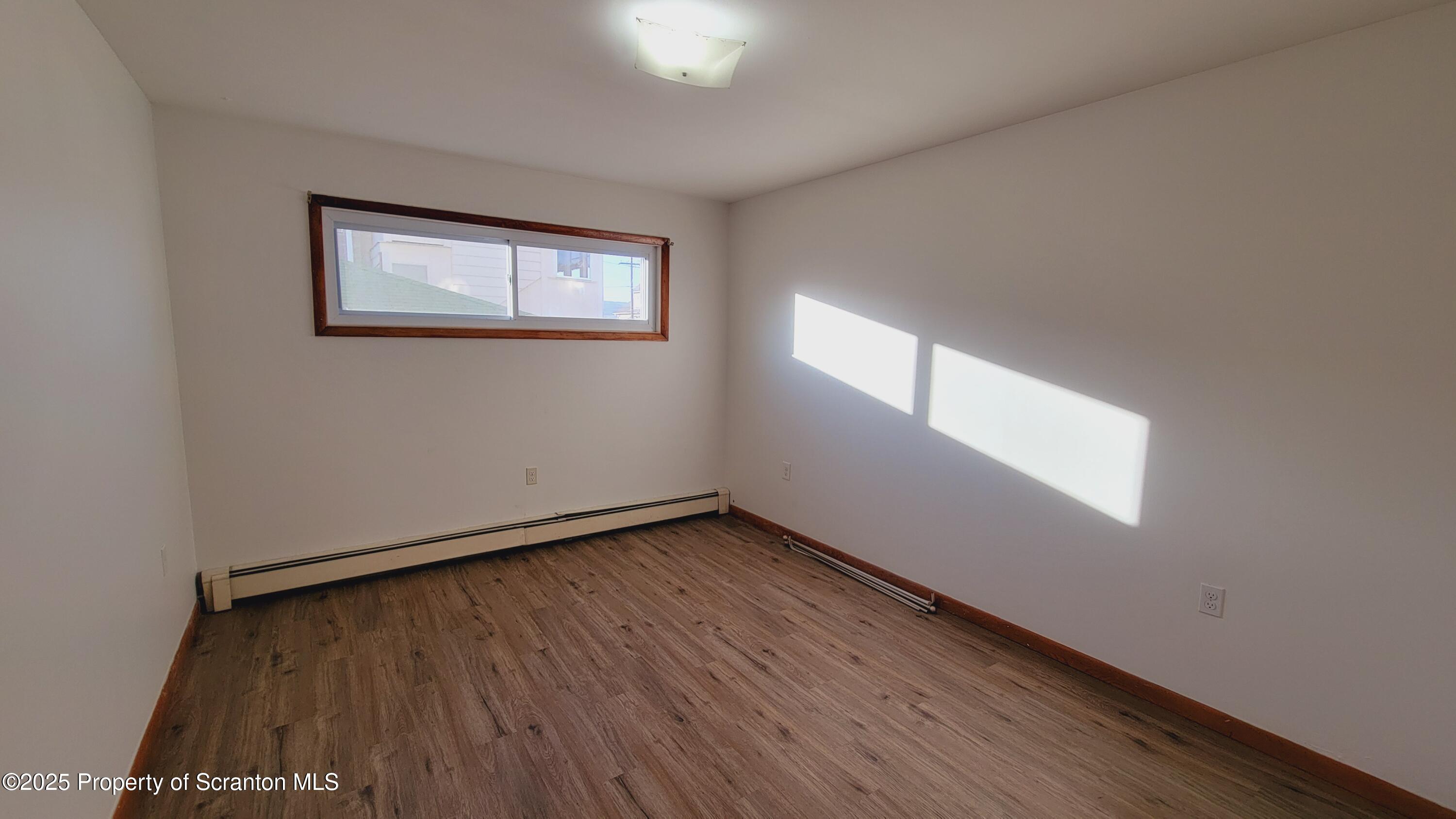 712 Alder Street, Unit FIRST Scranton, PA 18505 - Photo 6 of 18 a view of an empty room with wooden floor and a window