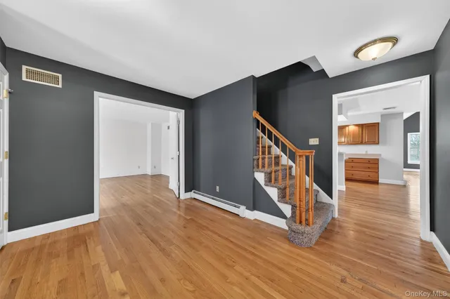 a view of an empty room with window and wooden floor