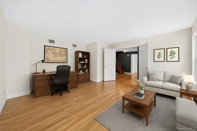 a living room with furniture couches and a dining table with wooden floor