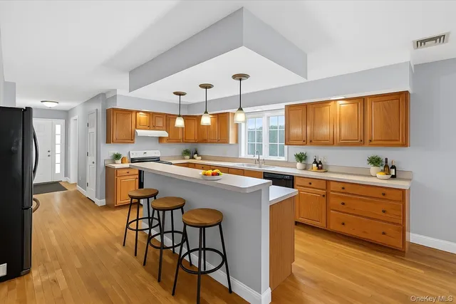 a kitchen with stainless steel appliances kitchen island granite countertop a table chairs sink and cabinets