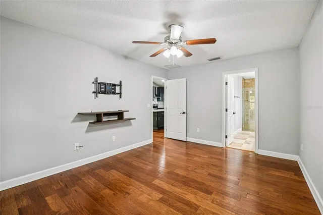 a view of an empty room with window and wooden floor