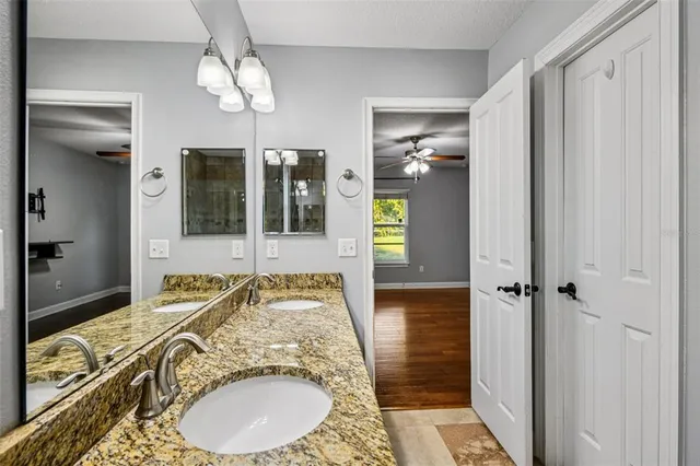a bathroom with a granite countertop sink a mirror and shower
