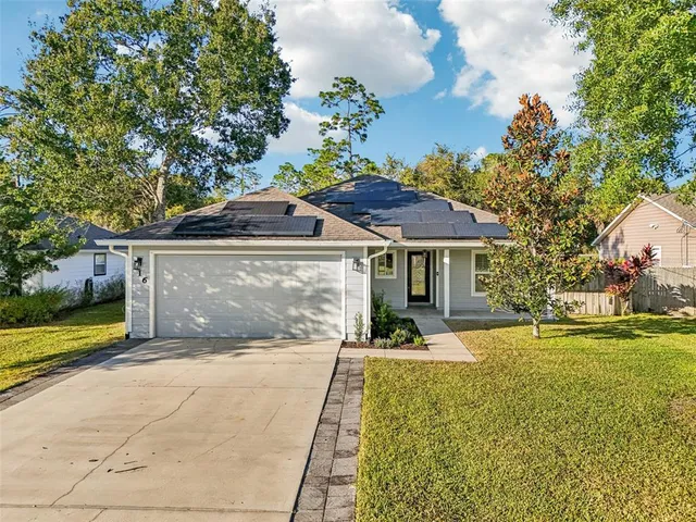 a front view of a house with a garden and trees