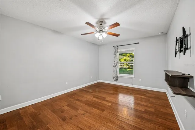 a view of an empty room with window and wooden floor