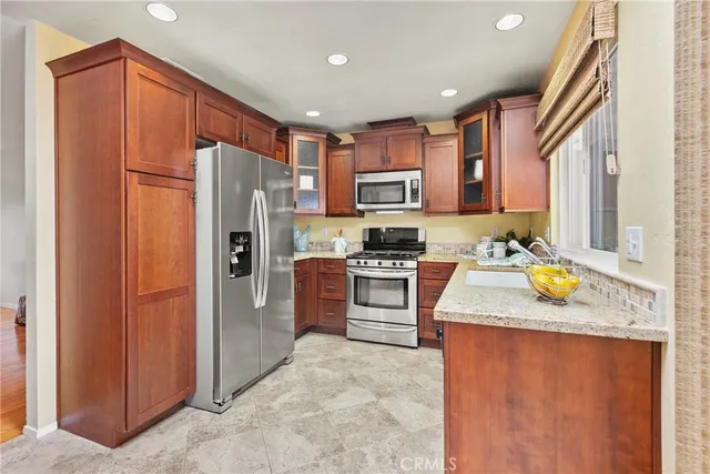 a kitchen with stainless steel appliances granite countertop a refrigerator a stove and a sink
