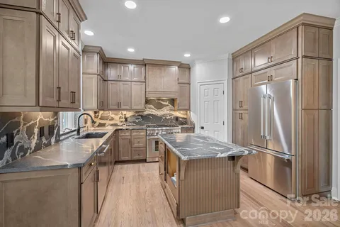 a kitchen with stainless steel appliances granite countertop a refrigerator a sink and a stove
