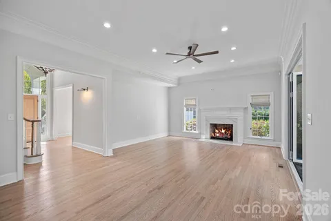 an empty room with wooden floor fireplace and windows