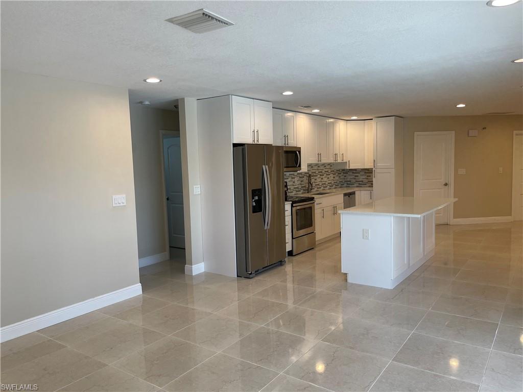 255 Pine Valley Circle Naples, FL 34113 - Photo 5 of 27 a view of a kitchen with refrigerator and chairs