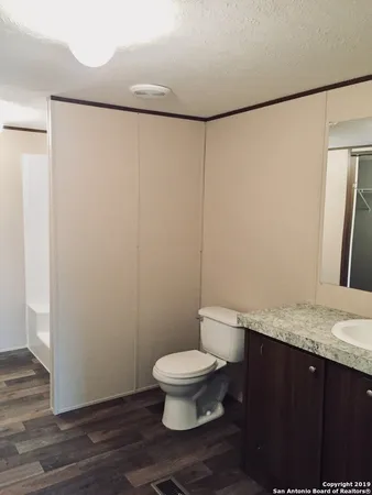 a bathroom with a granite countertop sink toilet and a mirror