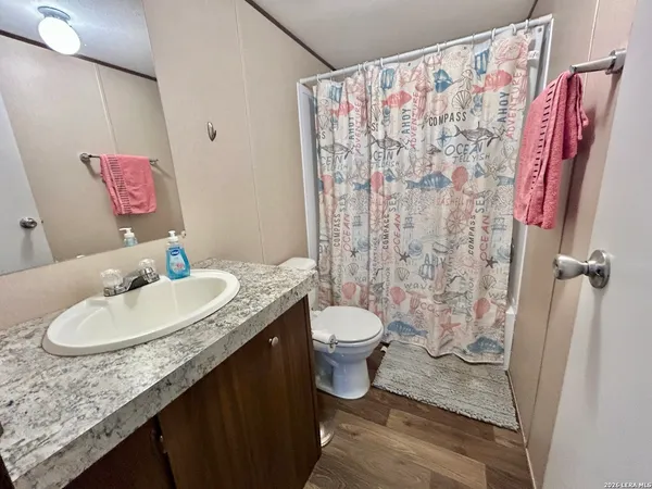 a bathroom with a granite countertop sink mirror vanity and toilet