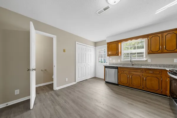 a kitchen with stainless steel appliances granite countertop a stove a sink and a refrigerator with wooden floors