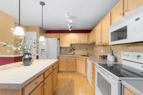 a kitchen with stainless steel appliances granite countertop a sink a stove and a wooden floors