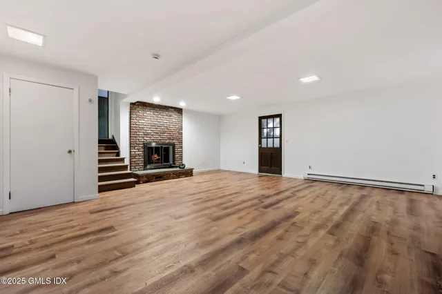 a view of an empty room with wooden floor and a fireplace