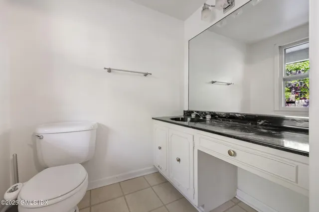 a bathroom with a granite countertop toilet and a sink