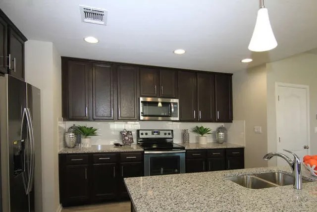 a kitchen with granite countertop wooden cabinets a refrigerator and a sink