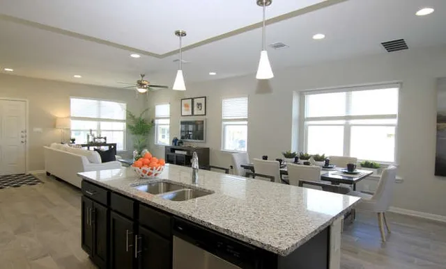 a kitchen with granite countertop a sink a counter top space and living room view
