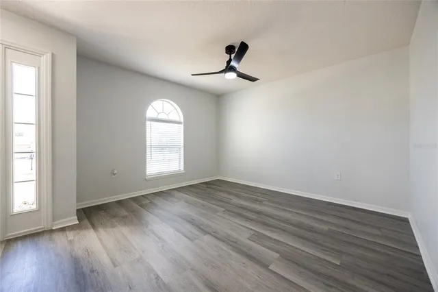 a view of a livingroom with wooden floor a ceiling fan and windows