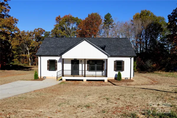 a front view of a house with a yard covered with trees